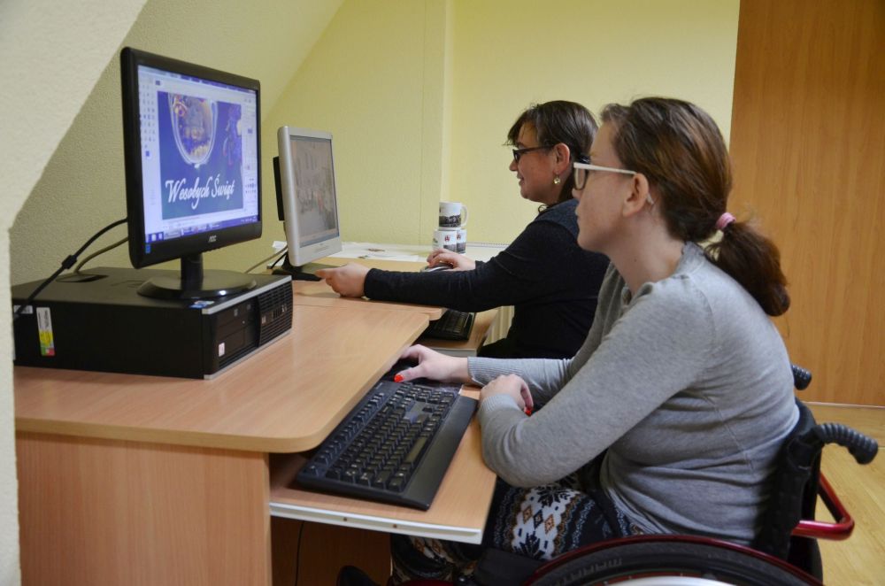 Zdjęcie przedstawia uczestniczki  podczas terapii zajęciowej w pracowni małej poligrafii. Uczestniczki obrabiają zdjęcia w programie GIMP.